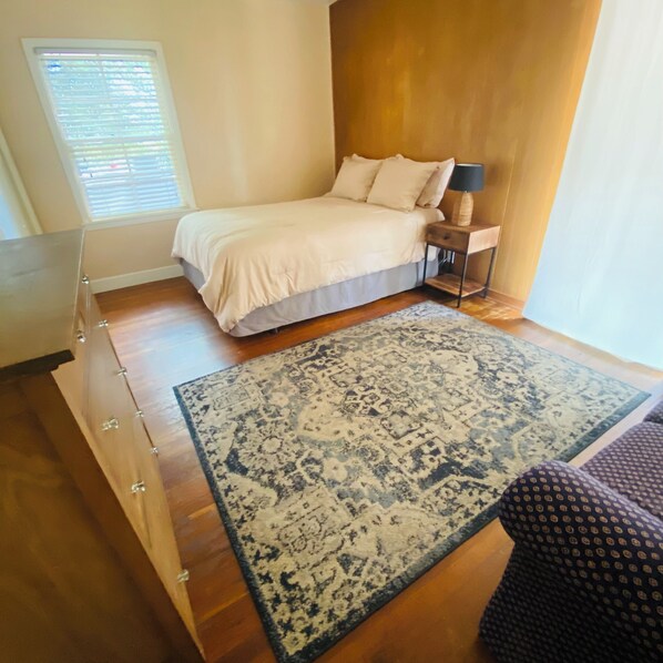 A bedroom with a bed, bedside table, lamp, and a patterned rug.