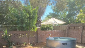 Un jardin avec une piscine, un mur en briques et une clôture en bois.