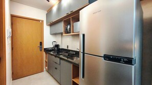 Una cocina moderna con un refrigerador de acero inoxidable, una cafetera y un horno empotrado.