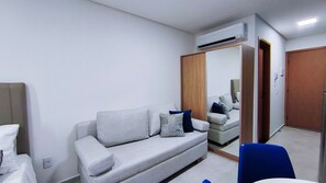 A modern hotel room with a sofa, a mirror, a wardrobe, and a chair. - Acqua Beach Residence (Tamandaré)