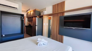Une chambre d’hôtel équipée d’un lit, d’une télévision, d’une kitchenette et d’une armoire.