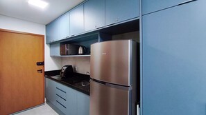 A kitchen with a stainless steel refrigerator, a coffee maker, and a microwave on the countertop. - Acqua Beach Residence (Tamandaré)