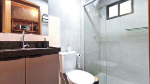 A modern bathroom with a glass shower enclosure, a sink with a marble countertop, and a toilet. - Acqua Beach Residence (Tamandaré)