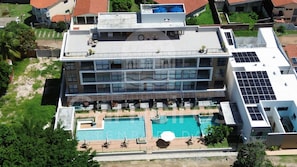 A multi-story hotel with a rooftop pool, solar panels, and a landscaped courtyard. - Acqua Beach Residence (Tamandaré)