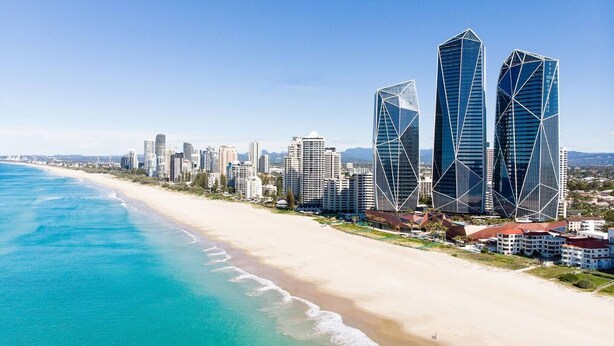 Eine Küstenstadt mit modernen Wolkenkratzern, einem Sandstrand und einem klaren, blauen Meer.
