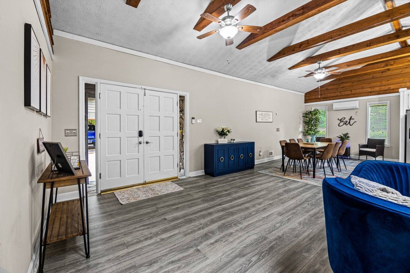 A spacious room with a dining area, a blue sofa, and a ceiling fan.