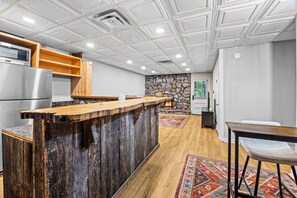 Une cuisine moderne dotée d’un îlot central en bois, d’appareils électroménagers intégrés et d’un mur d’accent en pierre.