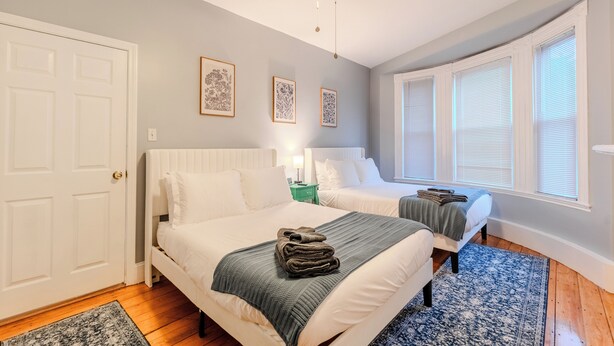 Ein Schlafzimmer mit zwei Betten, einem Deckenventilator und gerahmten Kunstwerken an der Wand.