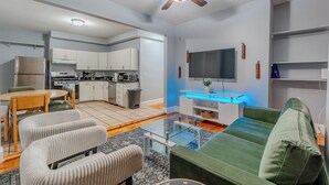 Ein modernes Wohnzimmer mit einem grünen Sofa, einem Glastisch und einem Deckenventilator.