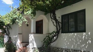 Un edificio con base de piedra y paredes blancas, una puerta de madera y una ventana.