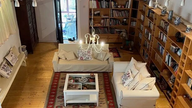 Una sala de estar acogedora con dos sofás blancos, una mesa de centro y una estantería llena de libros.