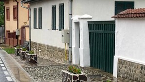 Una calle con edificios tradicionales, macetas de piedra con plantas y una verja verde.