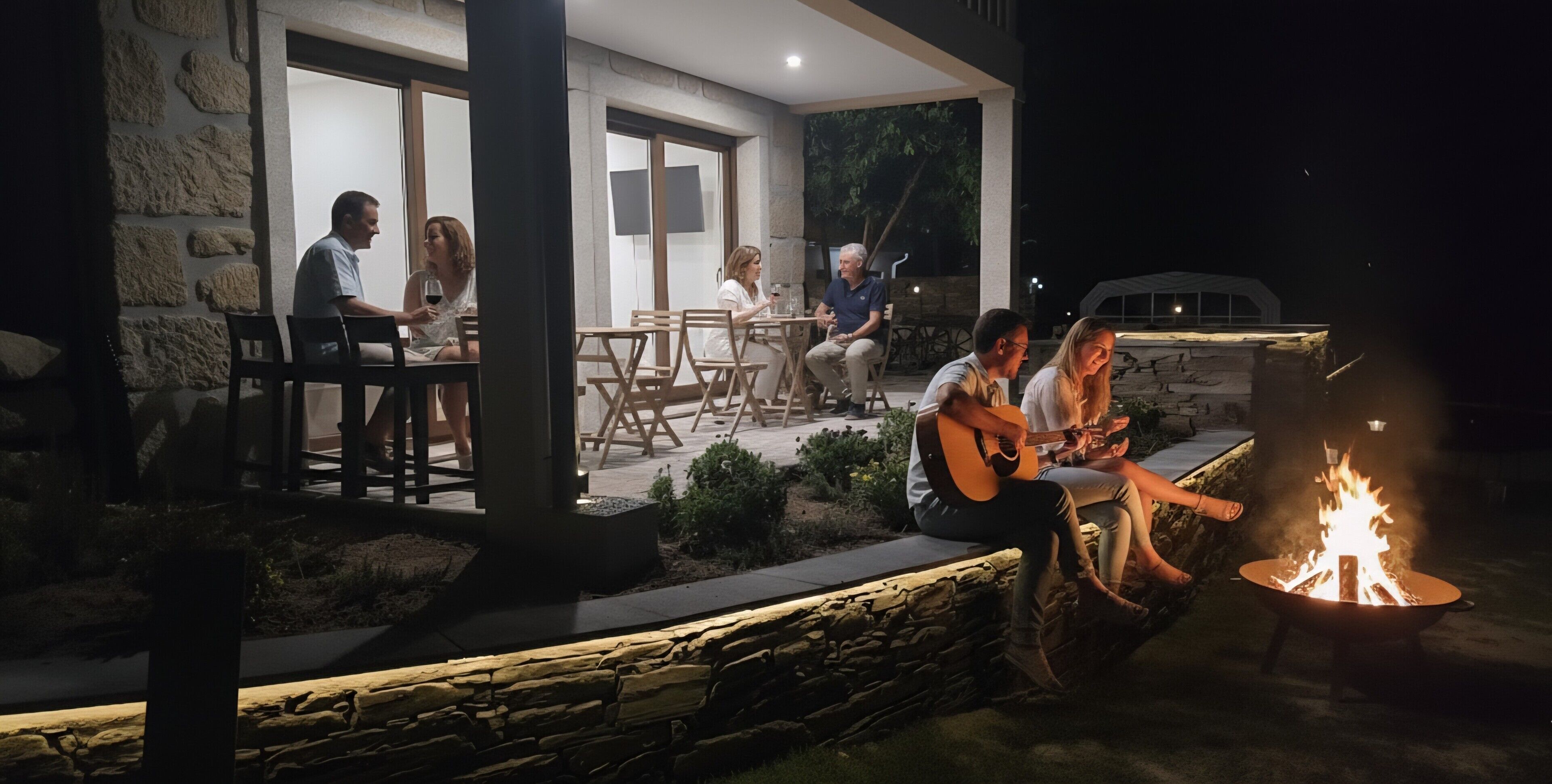 Un patio al aire libre con muros de piedra, muebles de madera y una chimenea.