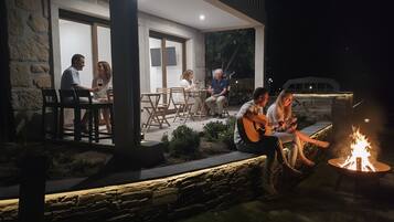Un patio al aire libre con muros de piedra, muebles de madera y una chimenea.