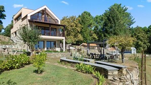 A two-story house with a balcony, stone walls, and a garden with a table and chairs. - Bed and Breakfast 'Piso Lua' with Mountain View and Heated Pool (Vila Real)