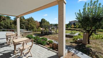 Eine überdachte Terrasse im Freien mit Holzmöbeln, einer Pergola und einem Gartenbereich.