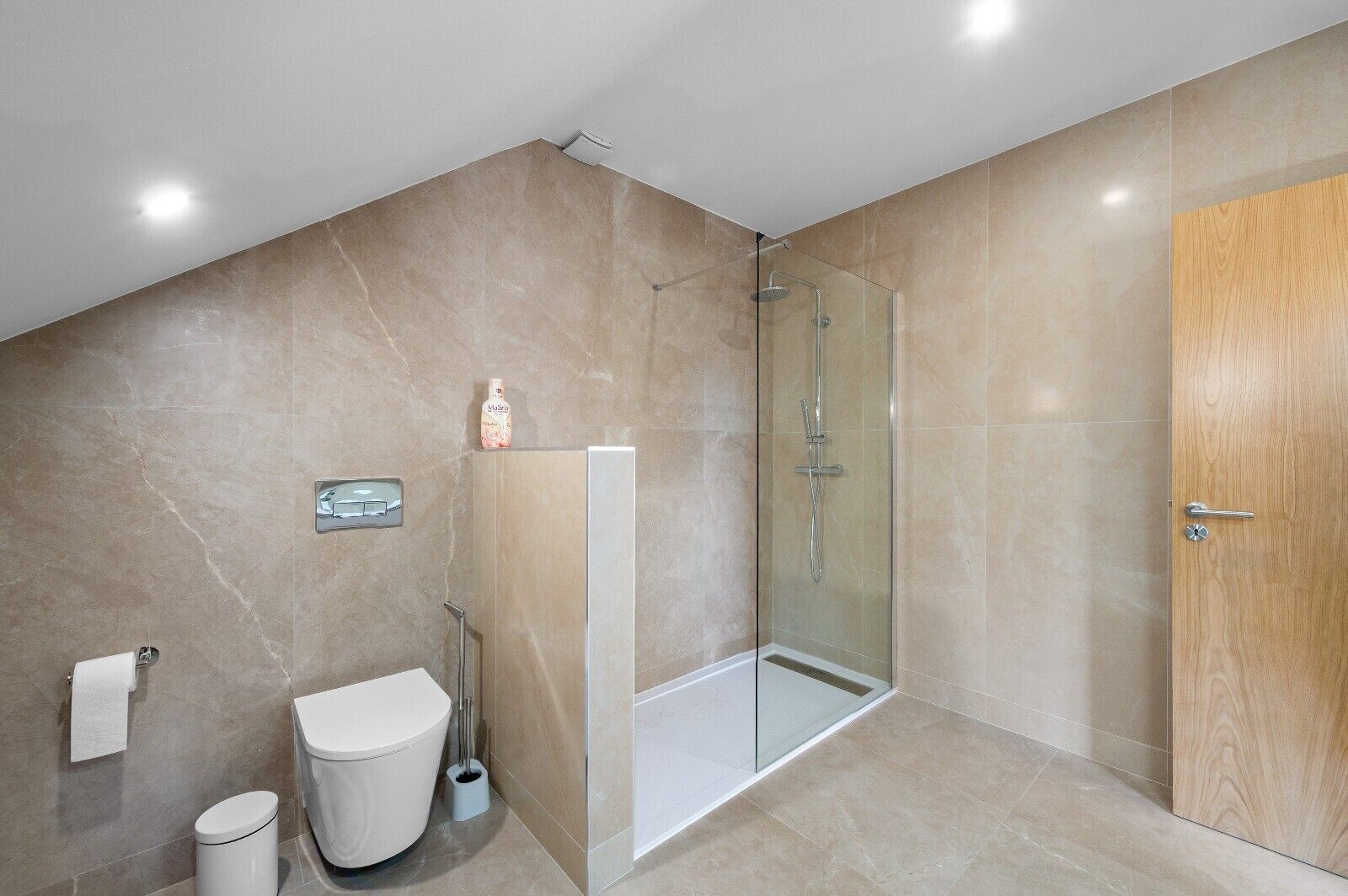 A modern bathroom with a glass-enclosed shower, a toilet, and a sink.