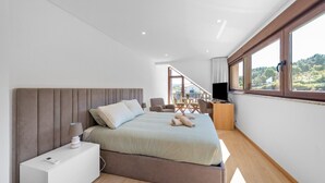 A modern bedroom with a bed, bedside table, TV, and a balcony with outdoor furniture. - Bed and Breakfast 'Piso Sol' with Mountain View and Heated Pool (Vila Real)
