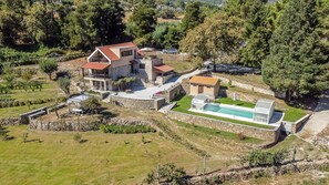 Ett stort hus med en swimmingpool, stenmurar och en trädgård.