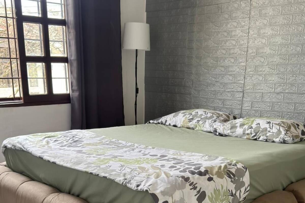 Un dormitorio con cama, lámpara y pared con diseño de ladrillos.