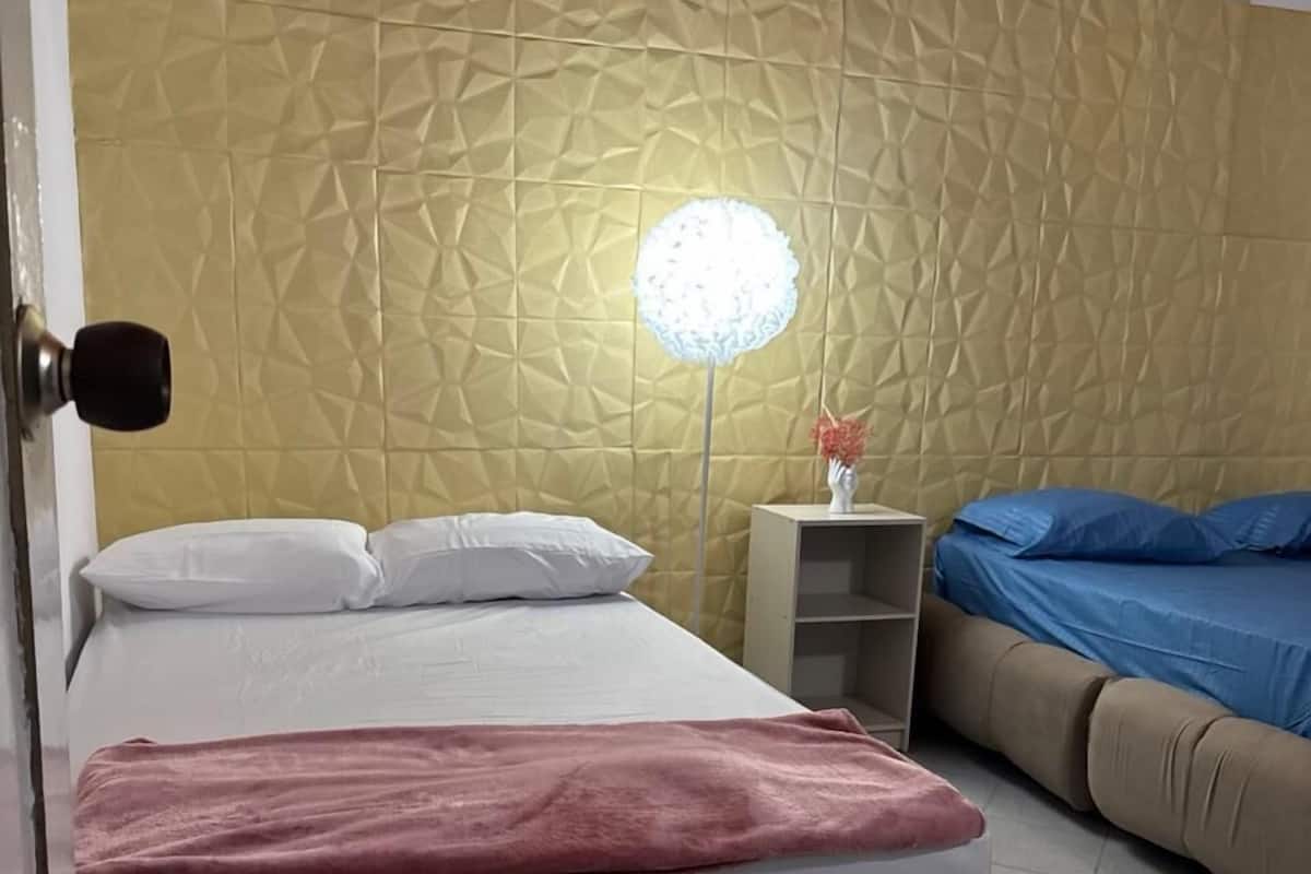 Un dormitorio con cama, mesita de noche, lámpara y sofá.