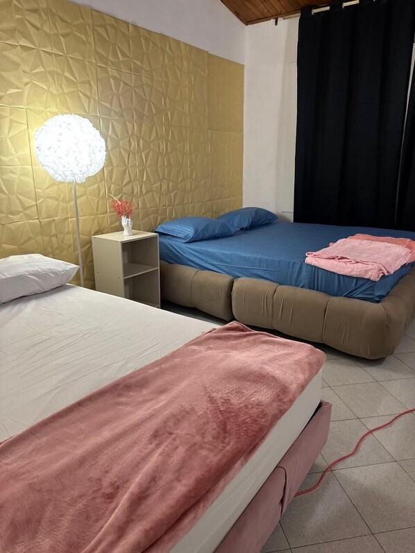 A bedroom with a bed, a bedside table, a lamp, and a wall with a geometric pattern. - Neoma Houses (Cali)