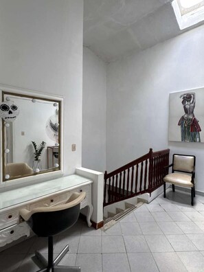 Un baño con tocador, espejo y una silla.