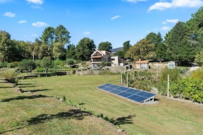 Ein Haus mit einer Solaranlage, einem Rasen und Bäumen.