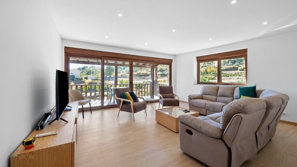 A spacious living room with a flat-screen TV, wooden furniture, and large windows offering a view of the outdoors. - Bed and Breakfast 'Piso Vénus - T1 with Heated Pool' and Mountain View (Vila Real)