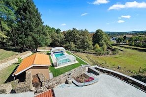 Ein modernes Haus mit Swimmingpool, Steinwänden und einem Garten.