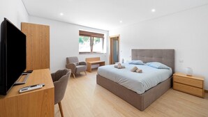 A modern bedroom with a bed, bedside tables, a desk, a chair, and a television. - Bed and Breakfast 'Piso Vénus - T1 with Heated Pool' and Mountain View (Vila Real)