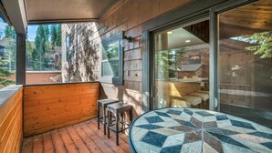 A wooden deck with a glass door leading to a seating area with a mosaic table. - Tahoe Donner Getaway | Ski-In/Ski-Out Retreat (Truckee)
