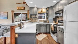 A modern kitchen with grey cabinets, a white countertop, a built-in oven, and a refrigerator. - Tahoe Donner Getaway | Ski-In/Ski-Out Retreat (Truckee)