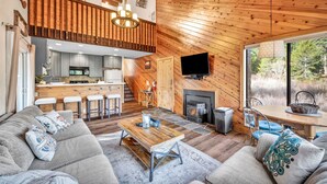 A cozy cabin interior with a living area, kitchen, and fireplace. - Tahoe Donner Getaway | Ski-In/Ski-Out Retreat (Truckee)