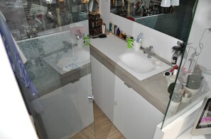 Ein Badezimmer mit weißem Waschbecken, einem Spiegel und verschiedenen Pflegeprodukten auf der Ablagefläche.