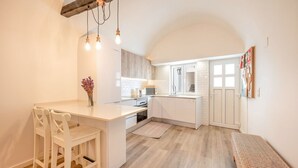 A compact kitchen with a central island, white cabinetry, and a hanging light fixture.