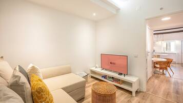 A modern living room with a sofa, a television, and a small table with books.