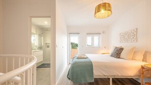 A bedroom with a bed, bedside table, and a hanging light fixture.