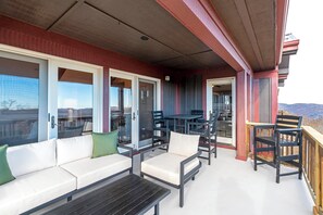 A covered outdoor seating area with a sofa, chairs, and a table. - Grand Oaks RQ6- Mountain Condo, Gated Resort, Indoor/Outdoor Pools & Hot Tub (Banner Elk)