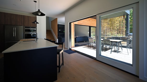 Uma cozinha moderna com uma ilha grande, eletrodomésticos embutidos e uma área de refeições com vista para um pátio externo.