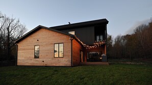 Uma casa moderna de dois andares com fachada de madeira e varanda decorada com luzes de cordão.