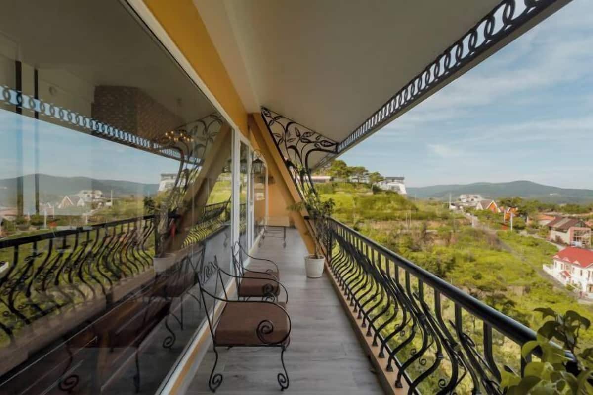 A balcony with a view of a green landscape and distant buildings.