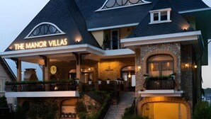 En byggnad med flera våningar, och en skylt som visar texten ”The Manor Villas”.