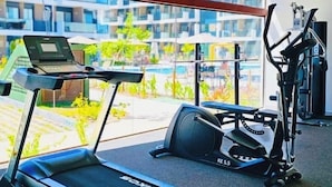 A gym with a treadmill, elliptical, and weight machine. - Makia Beach Experience Resort - Muro Alto, Porto de Galinhas - B18 POOL FRONT (Ipojuca)