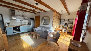 A modern kitchen with a built-in oven, a dining area with wooden furniture, and a cozy living space with a sofa and a coffee table. - Le Panorama with views of the Valley (Soultzeren)