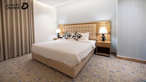 Een hotelkamer met een groot bed, twee nachtkastjes met lampen, een houten hoofdeinde en een vloerbedekking.