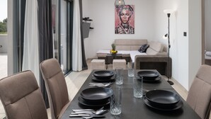 Un comedor moderno con una mesa negra para cuatro personas, un sofá y un cuadro en la pared.