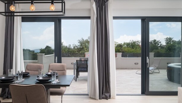 Un comedor moderno con una mesa preparada para cuatro personas, ventanas amplias y vistas al exterior.