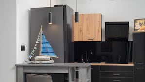 Una cocina moderna con refrigerador empotrado, armarios de madera y una pequeña decoración de velero sobre la encimera.