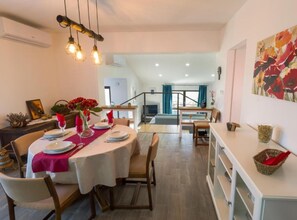 A dining area with a round table set for four, a staircase leading to an upper level, and a large floral painting on the wall. - Istra Green Soul Apartment (Oprtalj)